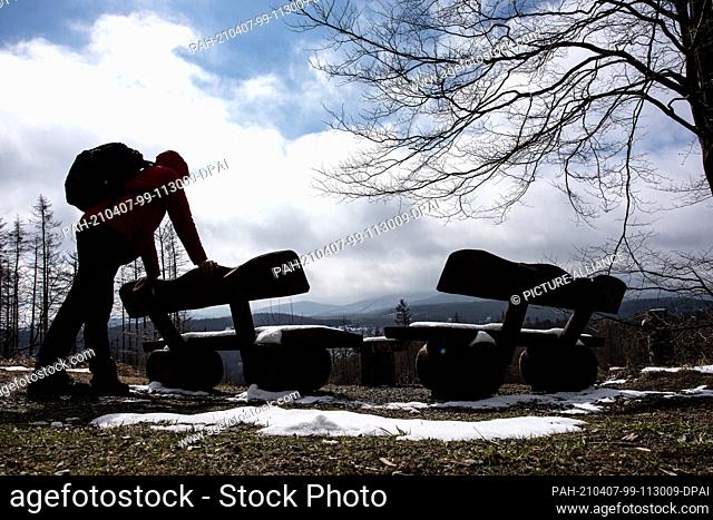 07 April 2021, Lower Saxony, Bad Harzburg: A hiker with a backpack stands at a bench near the Rabenklippen in the Harz National Park