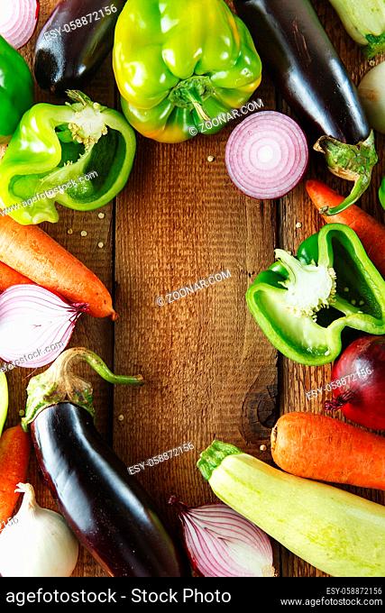 Fresh vegetables and ingredients for cooking around vintage cutting board on rustic background, top view, place for text