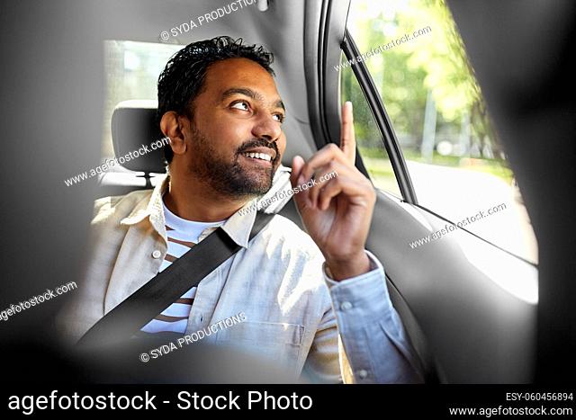 smiling indian male passenger in taxi car