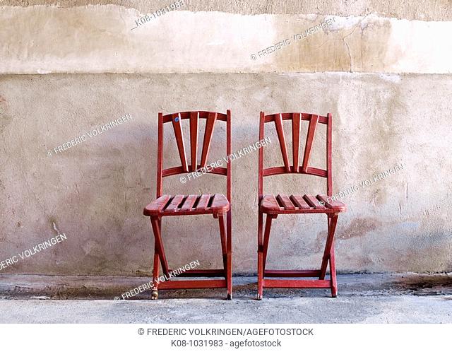Two red folding chairs against wall