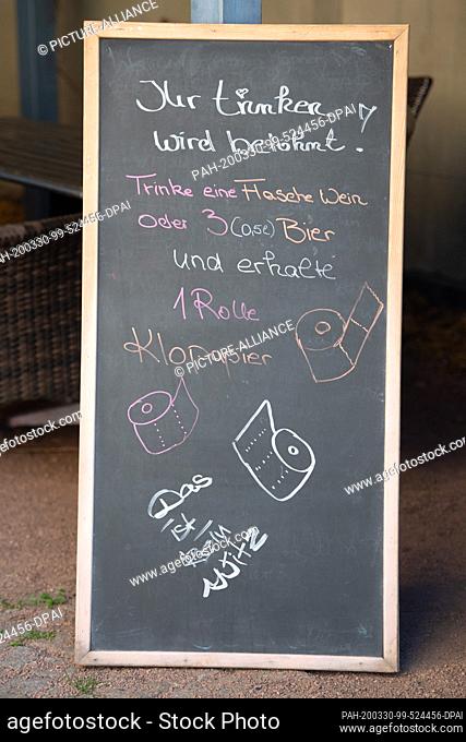 30 March 2020, Saxony, Radebeul: On the blackboard of a restaurant the offer of drinks and the addition of a roll of toilet paper is advertised