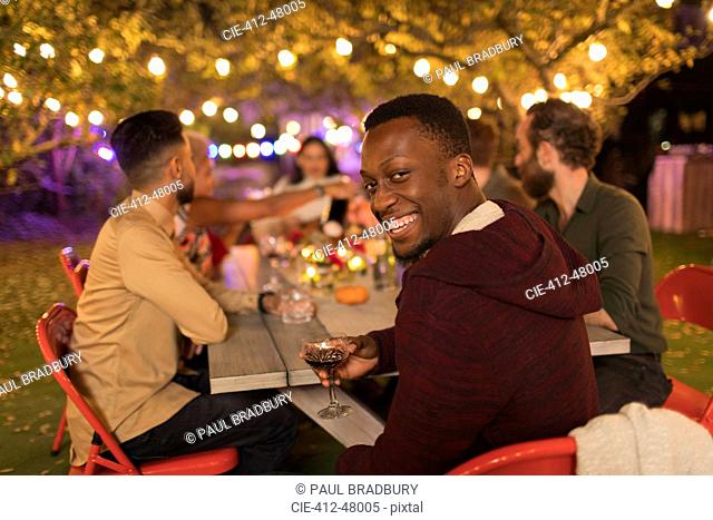 Portrait smiling man drinking wine, enjoying dinner garden party