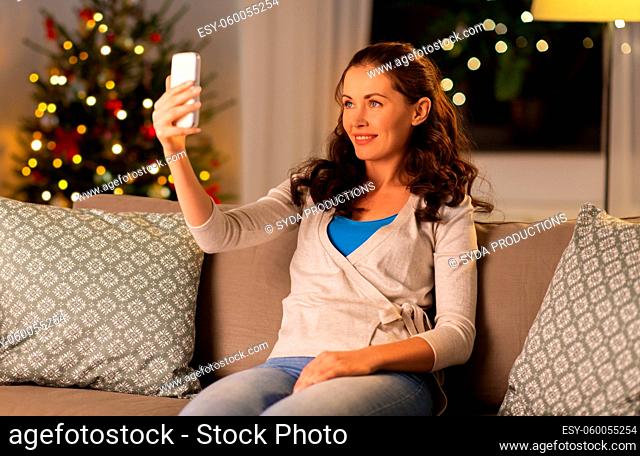 happy woman taking selfie with smartphone at home