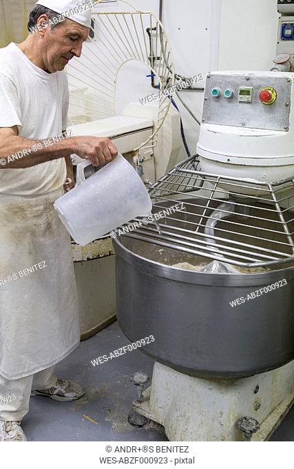 Baker pouring water in an industrial kneading machine