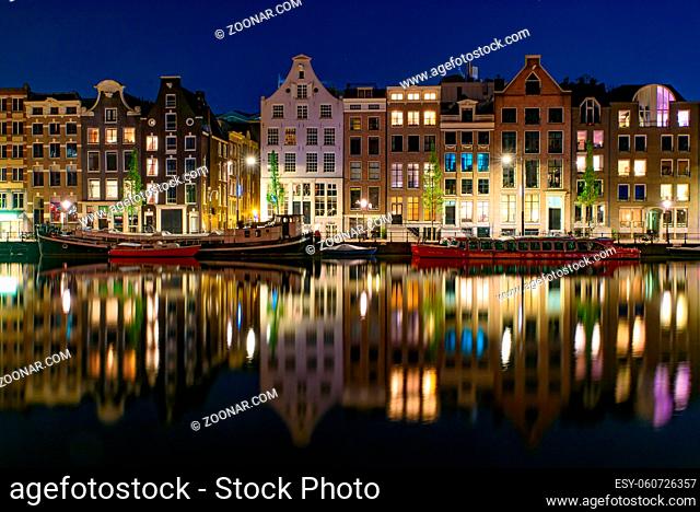 Reflection of the buildings along the canal at night in Amsterdam, Netherlands
