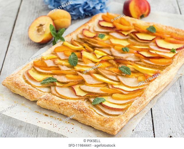 A fruit tart with slices of pear, peach, nectarine and apricot