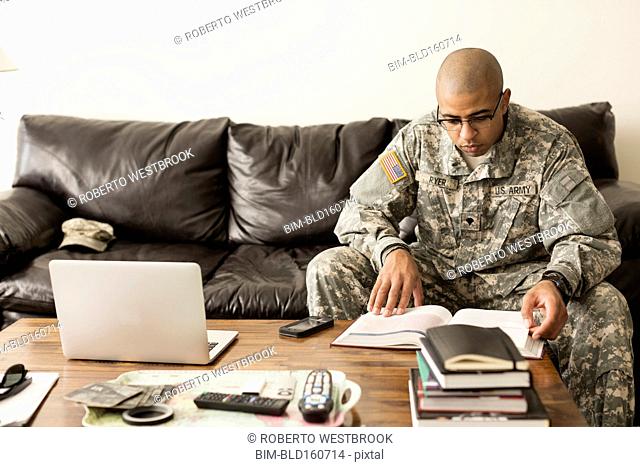 Mixed race soldier studying on sofa
