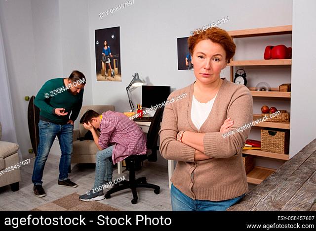 Tired mom and foreground arguing son and father on background. Problem of addiction to computer among teenagers