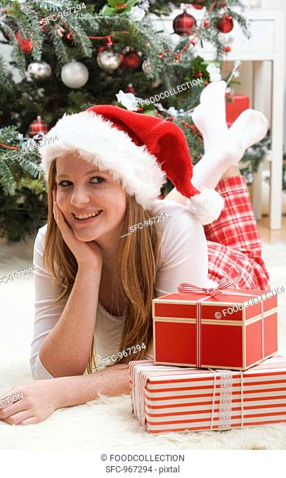 Woman in Father Christmas hat beside Christmas gifts