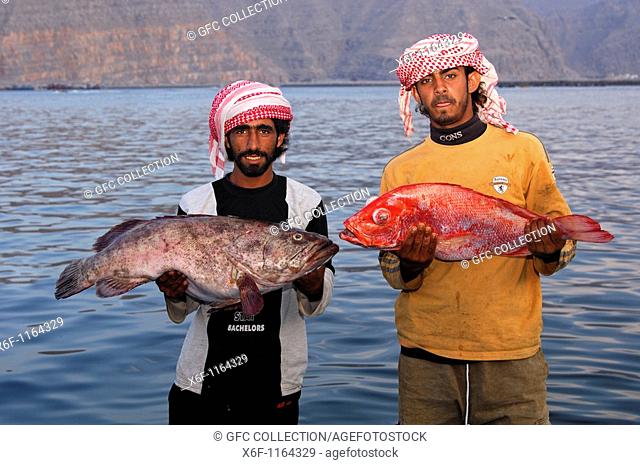 Two local Omani fishermen proudly present their catch, Musandam, Sultanate of Oman