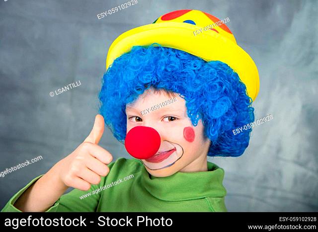 young child dressed as a clown with wig and fake nose smiling and thumbs up