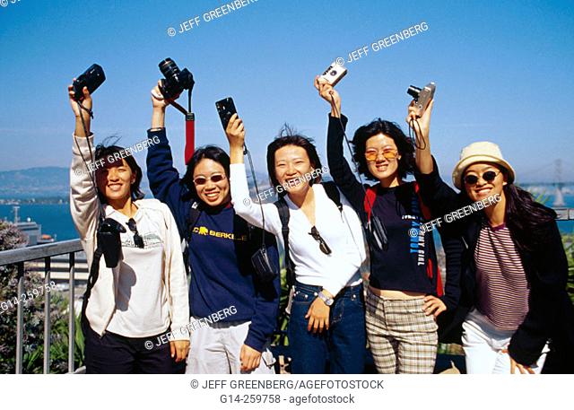 Asian female tourists from Taiwan showing their cameras at Telegraph Hill. San Francisco. California, USA