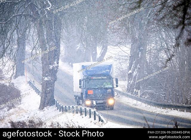 06 December 2023, Mecklenburg-Western Pomerania, Qualitz: A truck drives through an avenue in heavy snow. Persistent snowfall and temperatures below freezing...