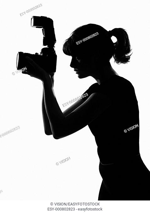 portrait silhouette in shadow of a young woman photographer holding a camera in studio on white background isolated