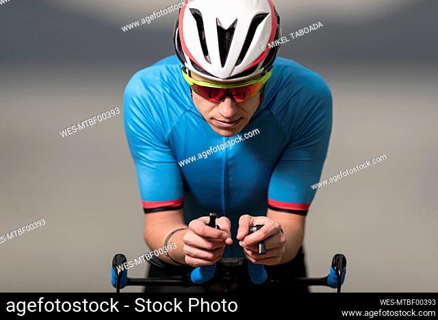Young male athlete in sports clothing riding racing bicycle