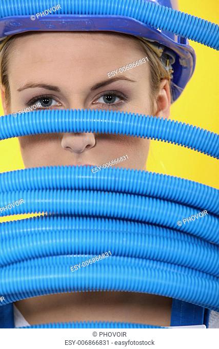 Female construction worker peeking through corrugated tubes