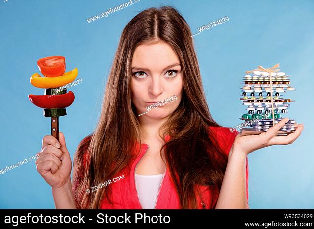 Woman girl holding vitamin tablets pills and vegetables. Choice between natural and synthetic vitamins. Health care. Healthy lifestyle nutrition concept