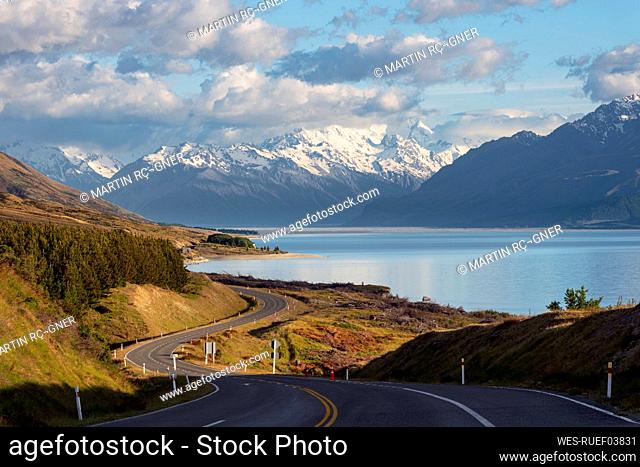 New Zealand, Canterbury Region, Winding asphalt road with Lake Pukaki and Mount Cook in background