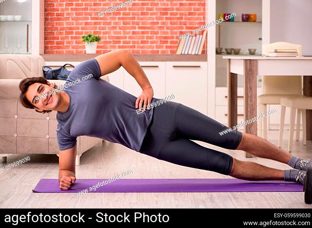 Young handsome man doing sport exercises at home