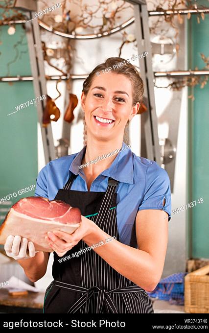 Portrait of beautiful butcher smiling with raw meat