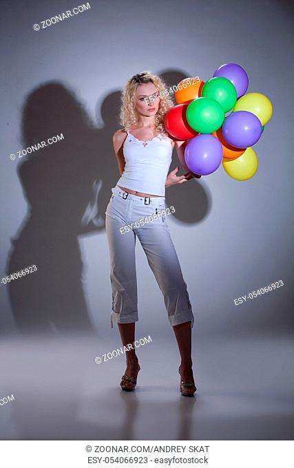 Young blonde beautiful woman in fashionable clothing with coloured balloons