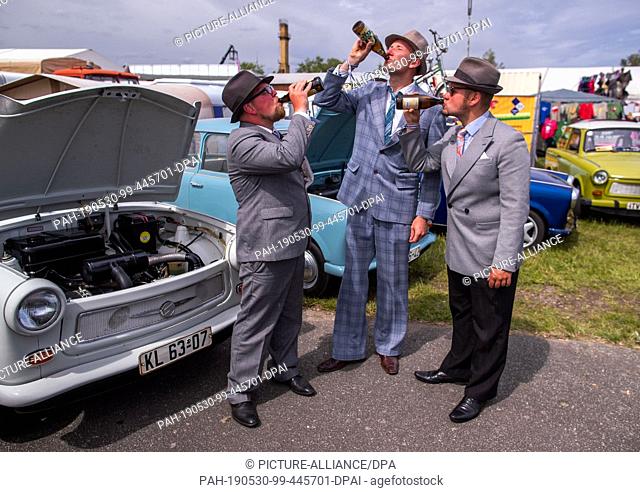 30 May 2019, Mecklenburg-Western Pomerania, Anklam: In front of their vehicles, three festively dressed gentlemen drink from their beer bottles on Father's Day...