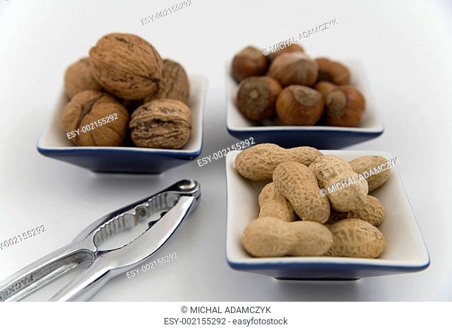 walnuts, hazelnuts and peanuts in three bowls