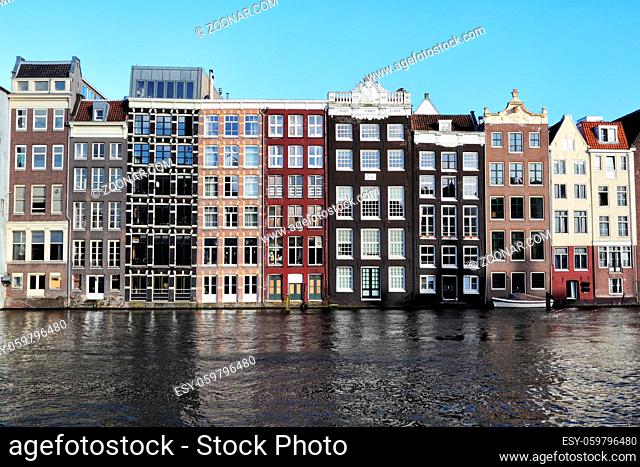 Typische Amsterdamer Häuser am Damrak in Amsterdam, Niederlande. Typical Amsterdam houses standing directly at the canal at Damrak in Amsterdam, Netherlands