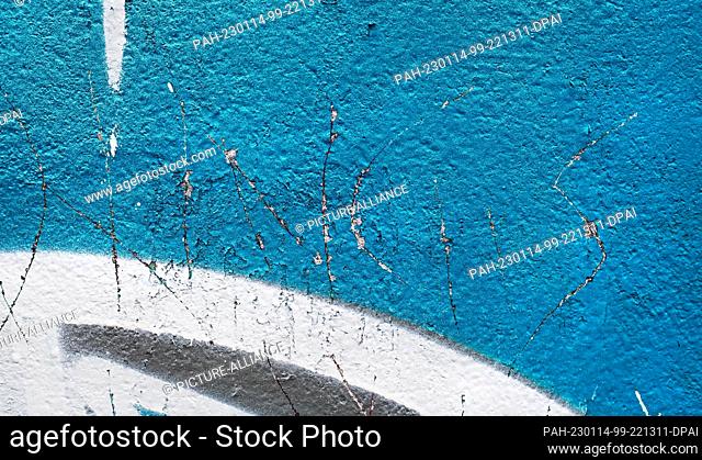 08 January 2023, Berlin: 08.01.2023, Berlin. Strokes are carved into the paint of old graffiti, forming colorful, random structures and patterns on a wall on...
