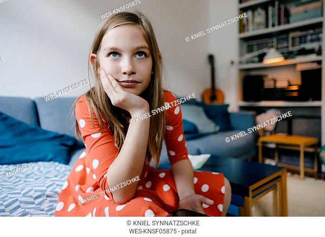 Portrait of serious girl sitting on couch at home