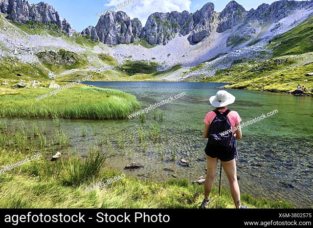Hiker woman and mountain glaciar lake. Ibon de Acherito route. Valles Occidentales Natural Park. Pyrenees Mountain Range