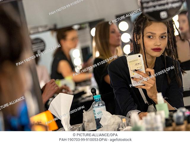 03 July 2019, Berlin: A model makes a selfie in the mirror in the backstage area before the show of designer Lena Hoschek