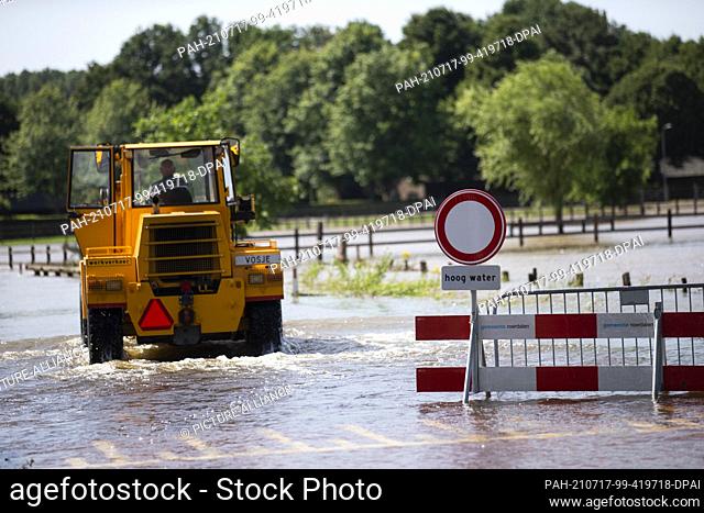 17 July 2021, Netherlands, Etsberg: In the municipality of Roerdalen roads and meadows are flooded. A roadblock with the warning sign ""Hoog Water"" has been...