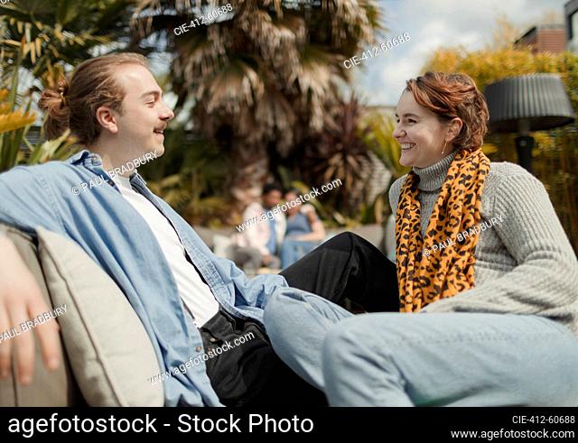 Happy young couple talking on sunny patio