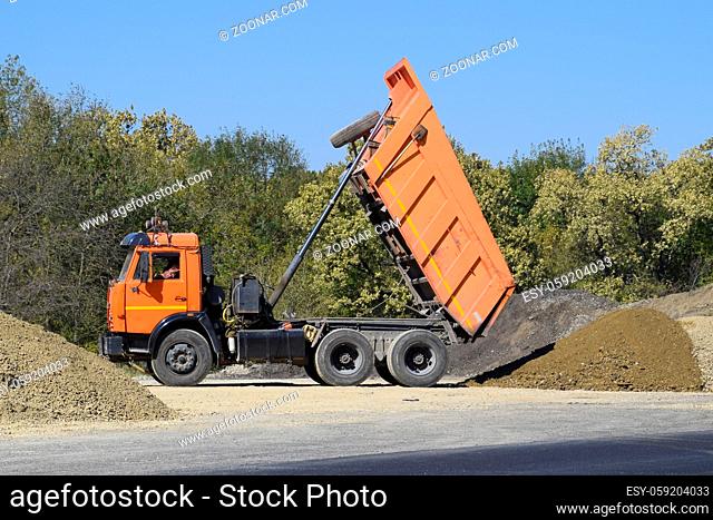 The dump truck unloads rubble. The truck dumped the cargo. Sand and gravel. Construction of roads