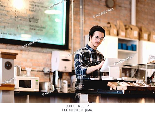 Cashier using cash register in cafe