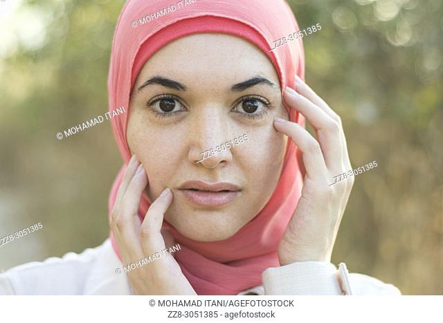 Beautiful Muslim woman wearing Hijab hands touching face