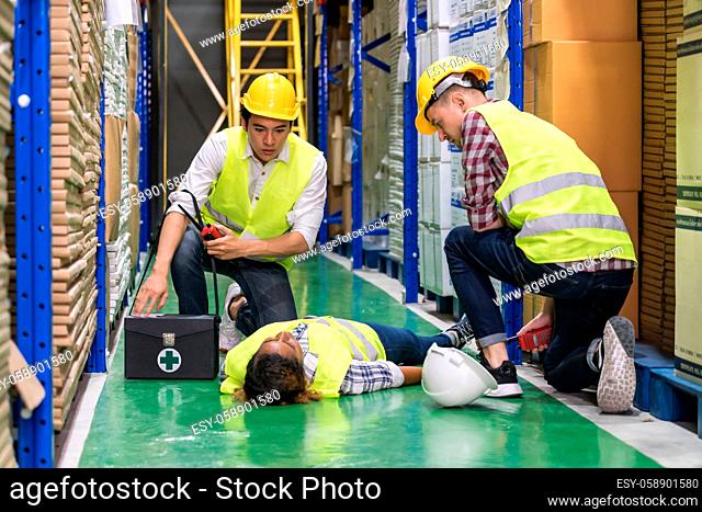 Warehouse worker do first aid to his colleague lying down on warehouse floor after accident while working. Using for industrial safety first and business...