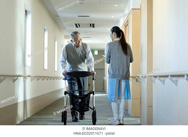 Senior man using mobility walker and care worker