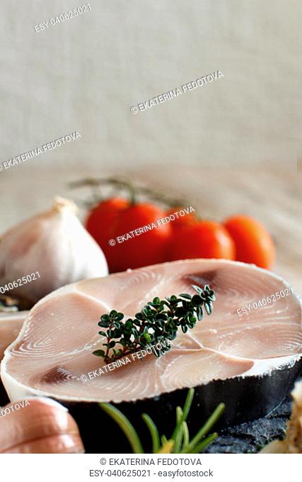 Shark steak on a wooden board with vegetables and herbs