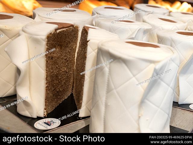 25 March 2020, North Rhine-Westphalia, Dortmund: A sliced ""toilet paper cake"" stands on a tray in the sales room. The round marble cake looks like toilet...