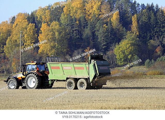 Salo, Finland - October 14, 2018: Farmer spreading manure on stubble field with Valtra tractor and Bergmann spreader on a beautiful day of autumn