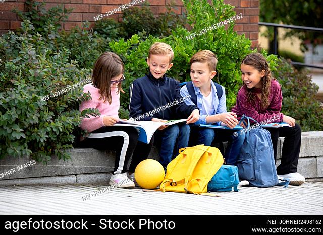 Children looking at school books in front of school building