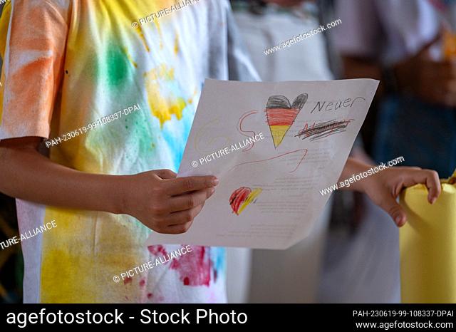 19 June 2023, Rhineland-Palatinate, Trier: A refugee child from the reception center for asylum seekers (AfA) in Trier sings from a sheet of paper on the back...