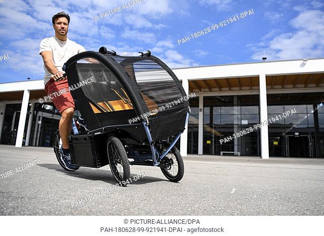28 June 2018, Germany, Friedrichshafen: The model Thomas drives a Cargobike Chike e-kids during a press conference, a week before the start of the bicycle fair...