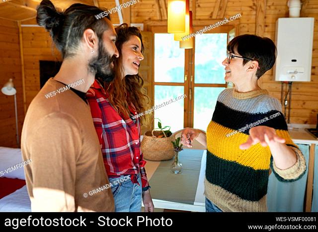 Host welcoming young couple in a cabin in the countryside handing over house key