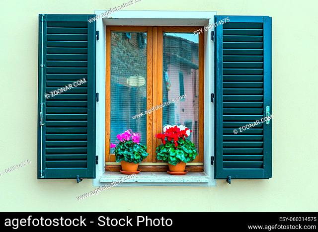 Cloudy autumn day in Tuscany. The small town of Montalcino. Beautiful element of window decor - shutters and cyclamens. The concept of cognitive