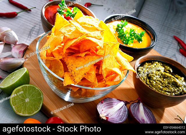 Composition with glass bowl of potato chips and dipping sauces