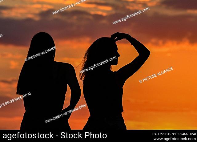 08 August 2022, Brandenburg, Jacobsdorf: Two girlfriends sitting in the sunset. Photo: Patrick Pleul/dpa. - Jacobsdorf/Brandenburg/Germany