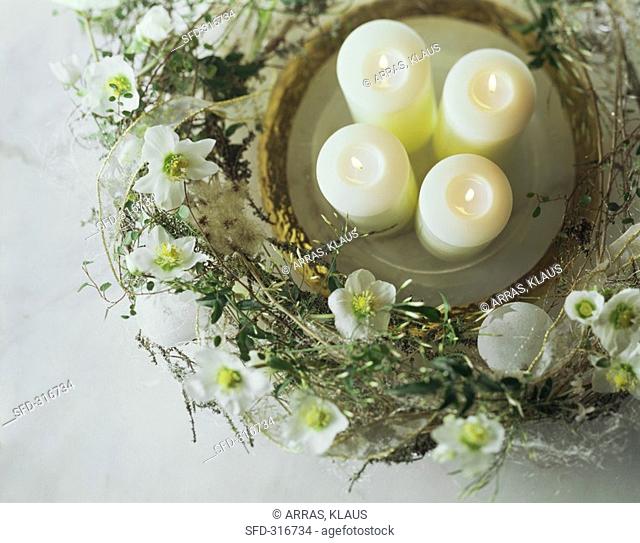 Four candles on plate surrounded by wreath of Christmas roses